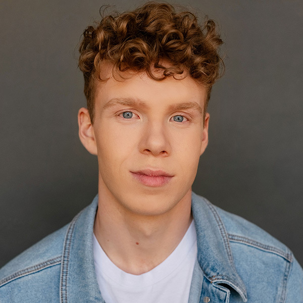 Bryce Johnson wearing a denim jacket in front of a grey background