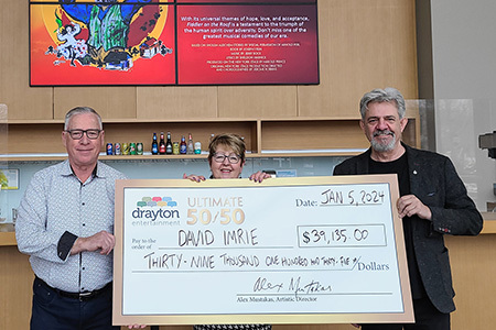 David and Wendy Imrie, along with Alex Mustakas, hold a big 50/50 cheque