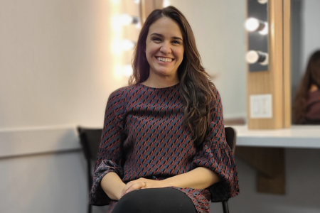 Photo of Emily Lukasik smiling as she sits in her dressing room at Hamilton Family Theatre Cambridge<