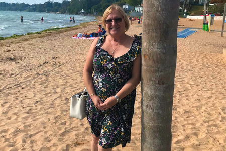 Meryl Penman standing on a sandy beach and smiling<