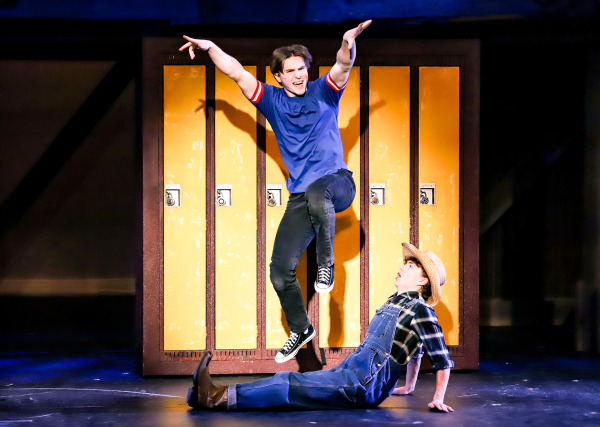 Production photo of Footloose showing two teenage boys dancing in front of school lockers.